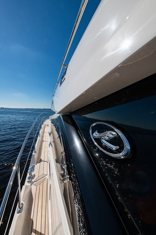 Polished hull emblem catching the sun along the side deck